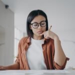 Female housewife in glasses calculates expenses, planning household budget for saving money at home